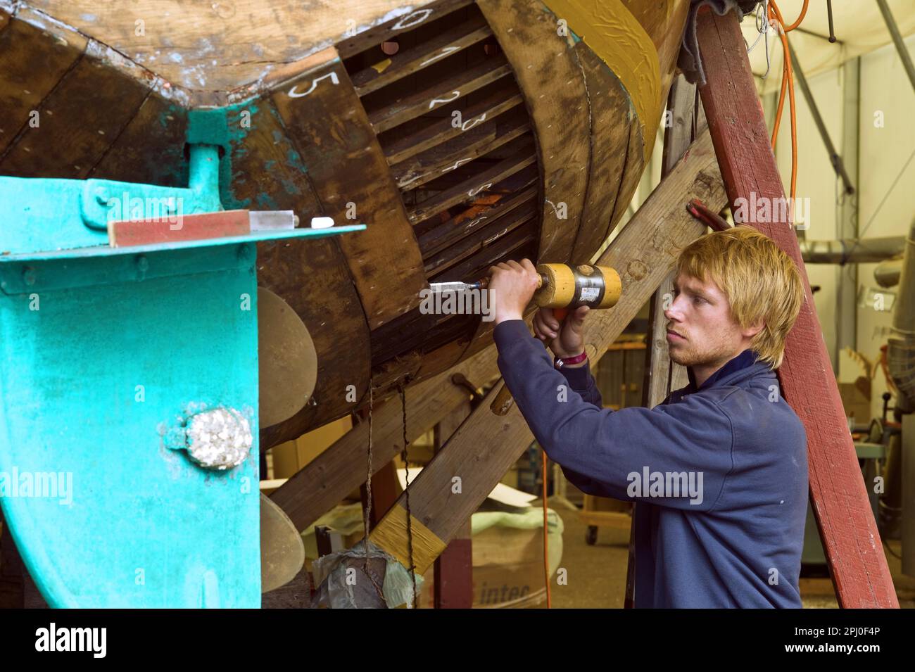 Boat builder restoring the hull of a wooden boat at the Winkler shipyard in Bremen Lesum, Germany Stock Photo