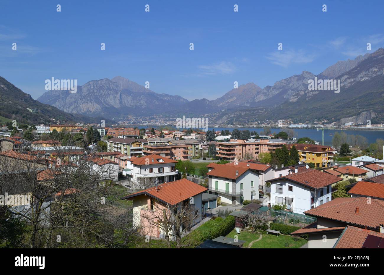 Beautiful panoramic view of the Lake Como district with town of Lecco in the background below mountain range.Modern Italian residence architecture. Stock Photo