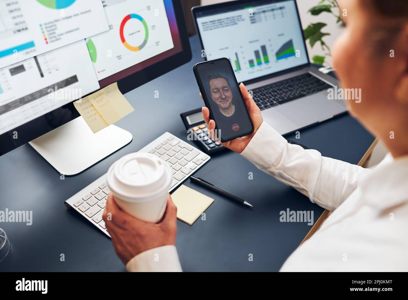 Woman entrepreneur having business video chat on smartphone. Businesswoman working with data on charts, graphs and diagrams on computer screen. Woman Stock Photo