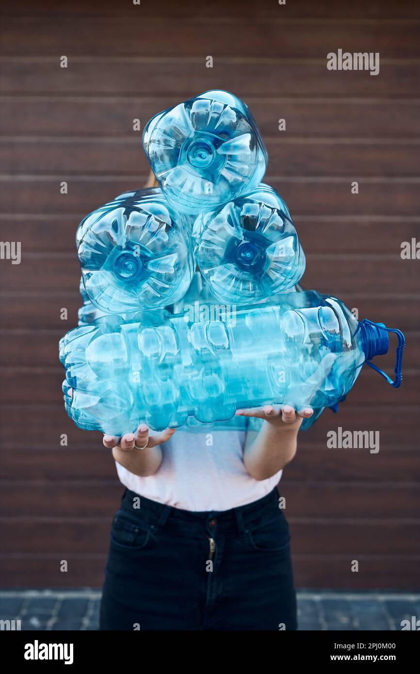 Young woman throwing out empty used plastic water bottles into trash