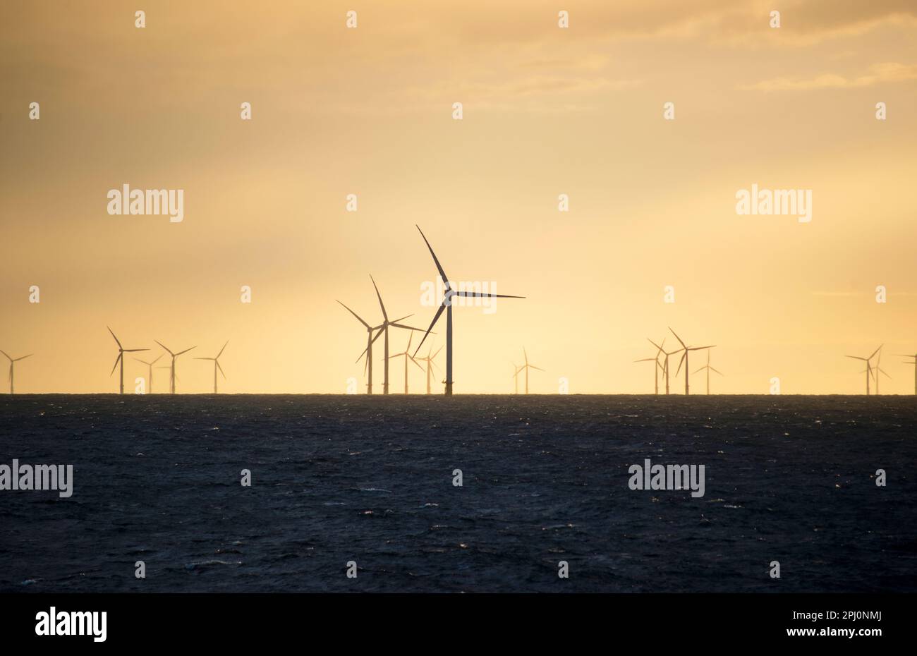 A windfarm at sea, with the turbines silhouetted against a bright sky. Green energy, electricity generation of the English coast at Galloper Wind Farm Stock Photo
