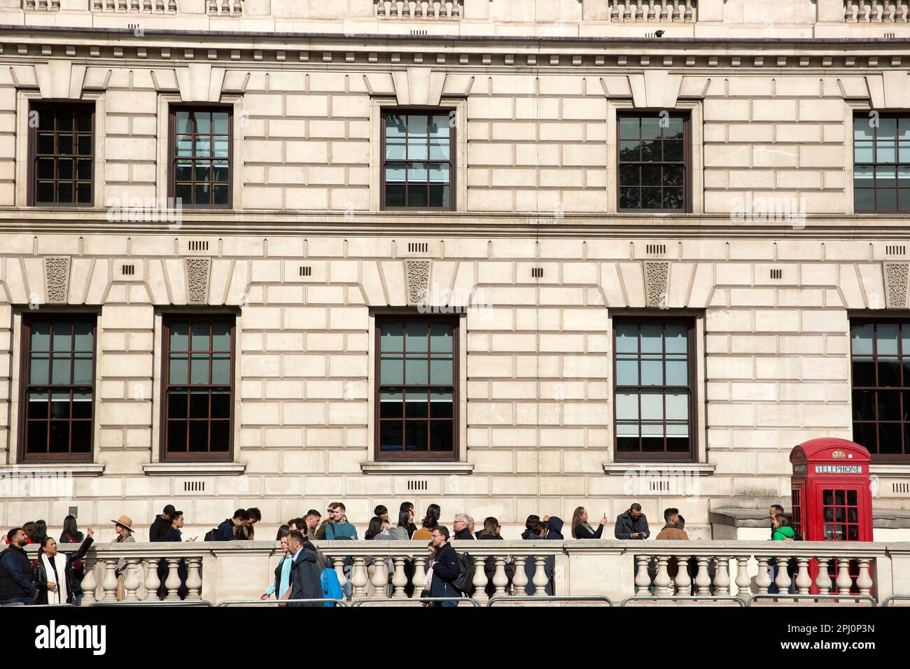 People queue to take photographs next to a red telephone box in