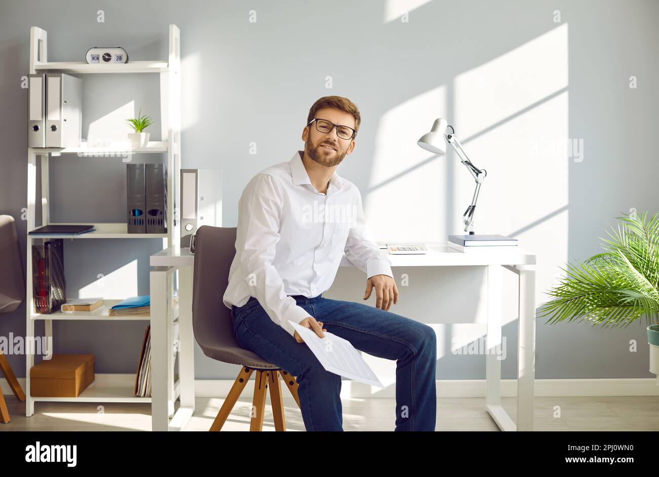 Portrait of young businessman sitting on chair at his workplace Stock Photo