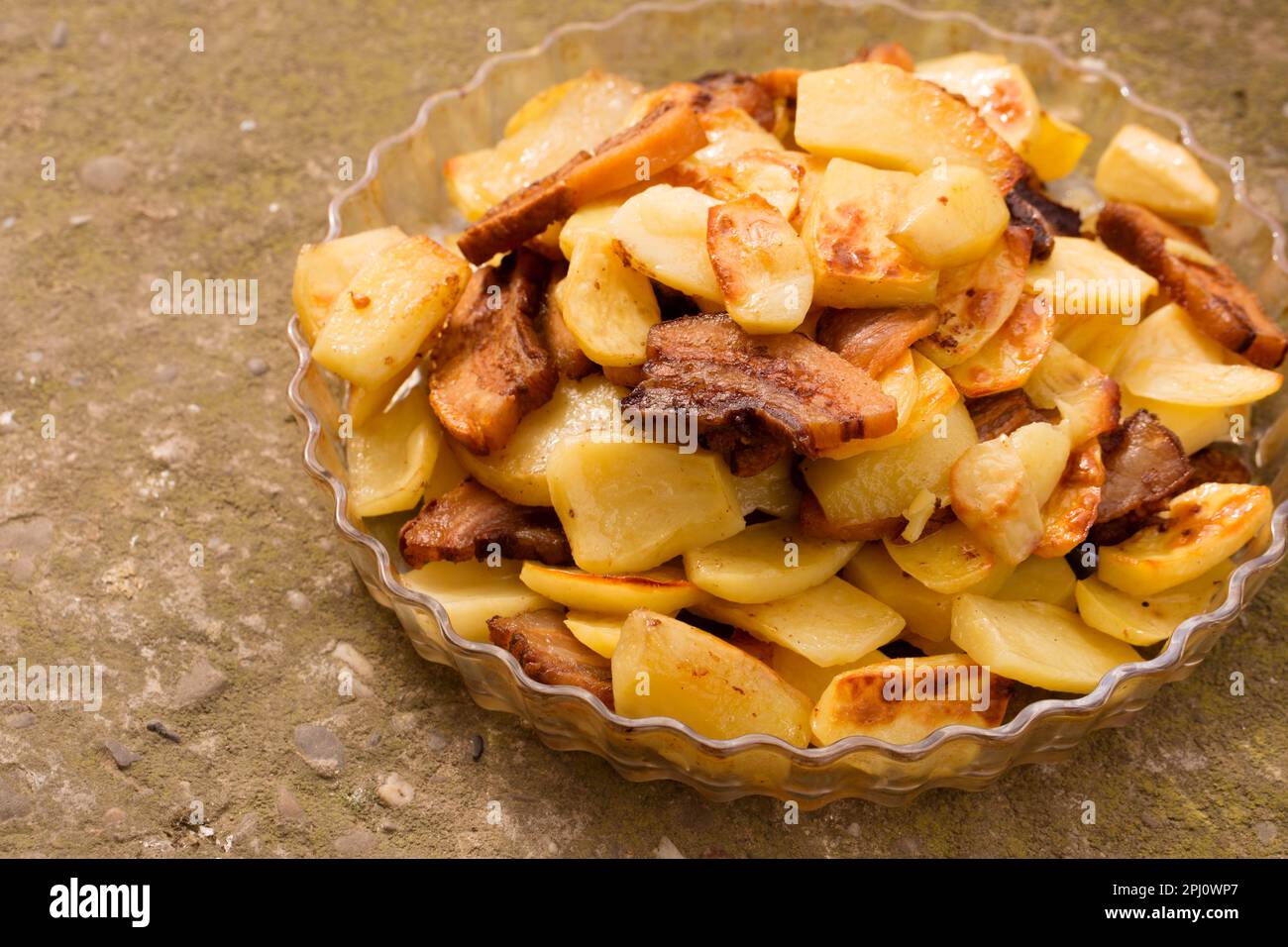 Crispy, ruddy fried potatoes with slices of fried lard on a large plate