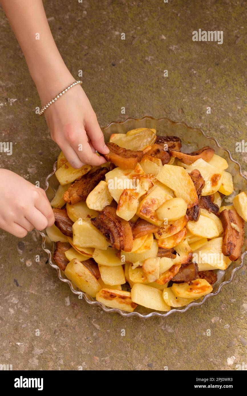 Crispy, ruddy fried potatoes with slices of fried lard on a large plate