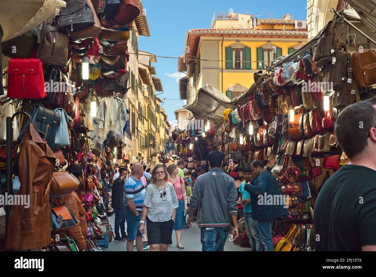 Crowds browse among the leather goods vendors on a narrow street outside the Central Market) on a bright sunny day in Florence, Italy, Stock Photo