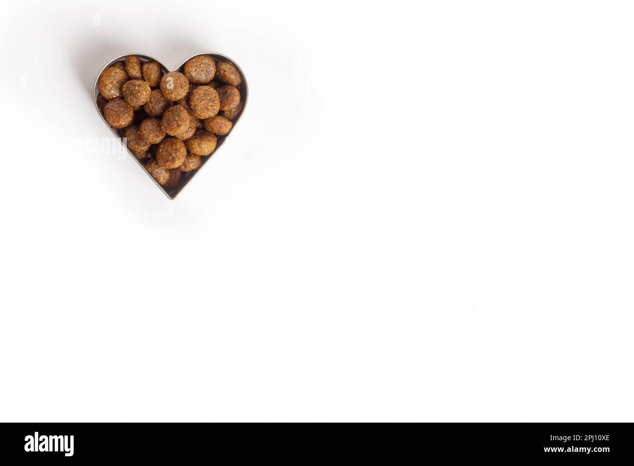 Dry pet food in the shape of a heart is isolated on a white background. Pellets of healthy food for dogs and cats. Taking care of pets. Healthy food f Stock Photo