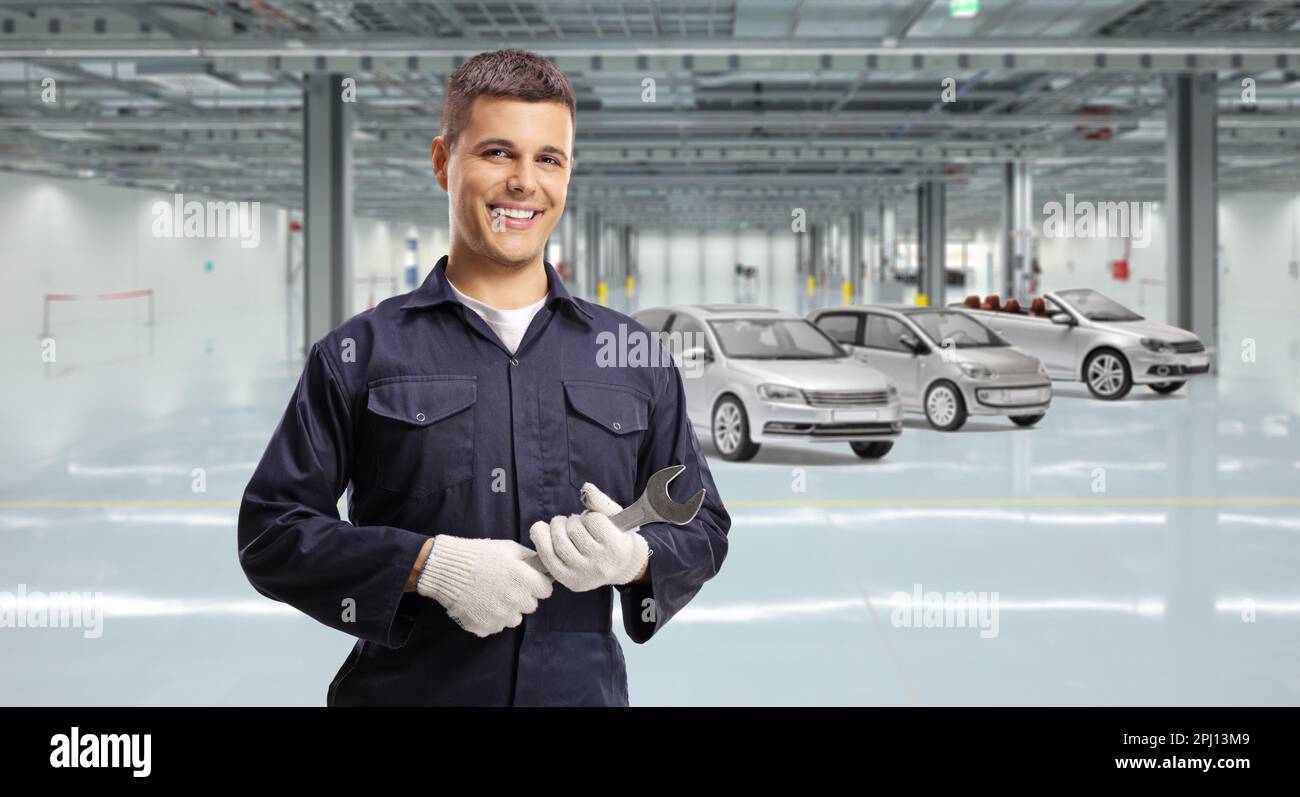 Smiling young mechanic holding a wrench inside a car garage Stock Photo ...