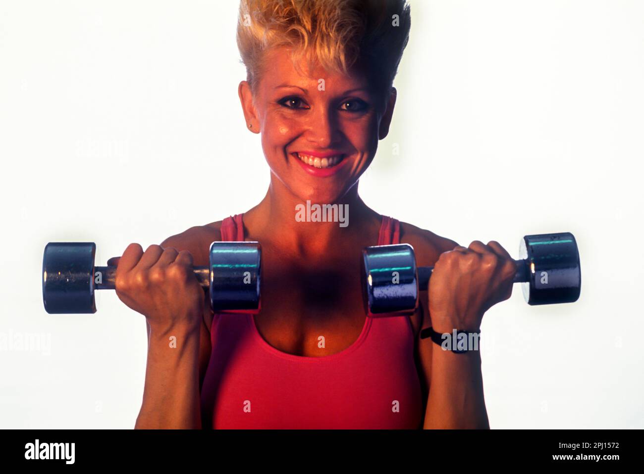 GYM YOUNG WOMAN WEIGHT LIFTER FLEXES ARM MUSCLES Stock Photo