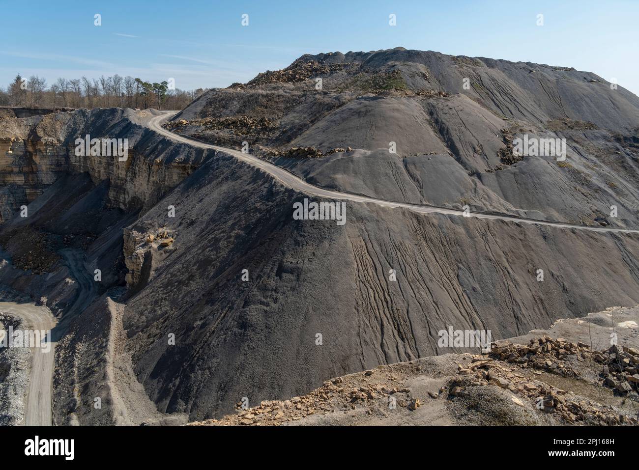 Scenery around a open-pit mine with gravel road, gravel and spoil piles in sunny ambiance Stock Photo
