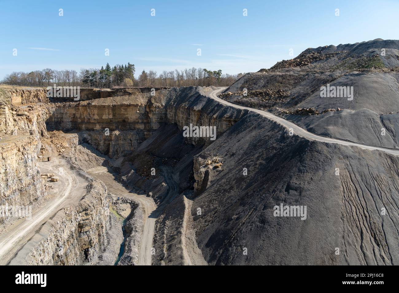 Scenery around a open-pit mine with gravel road, gravel and spoil piles in sunny ambiance Stock Photo