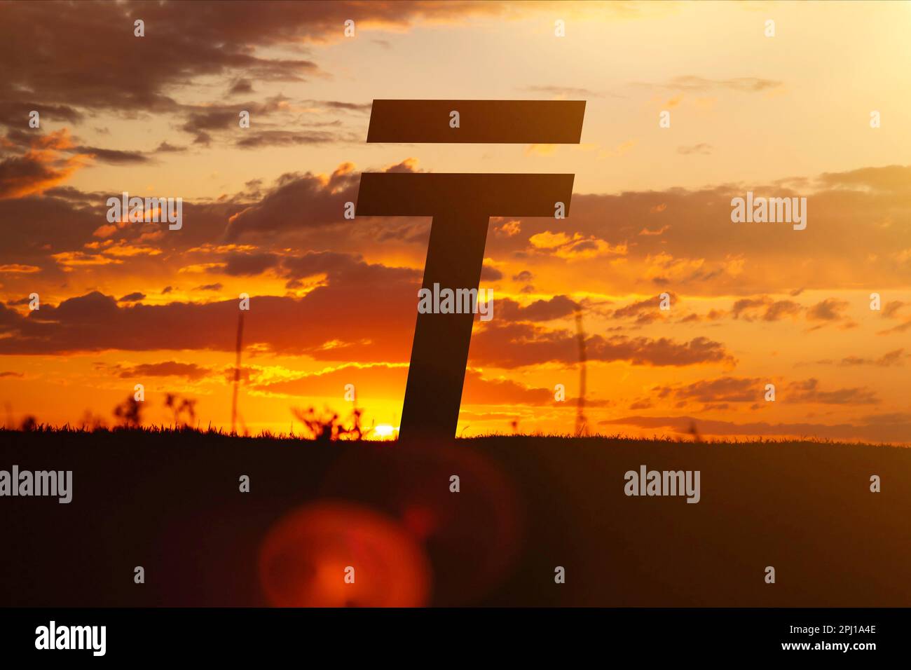 Tenge money sign at sunset in the rays of the setting sun. Sunset currency. Devaluation of money.. Stock Photo