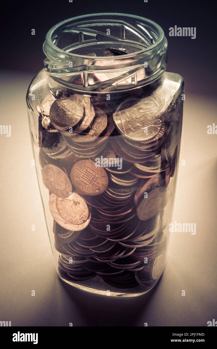 A glass jar coin collection for a rainy day. Stock Photo