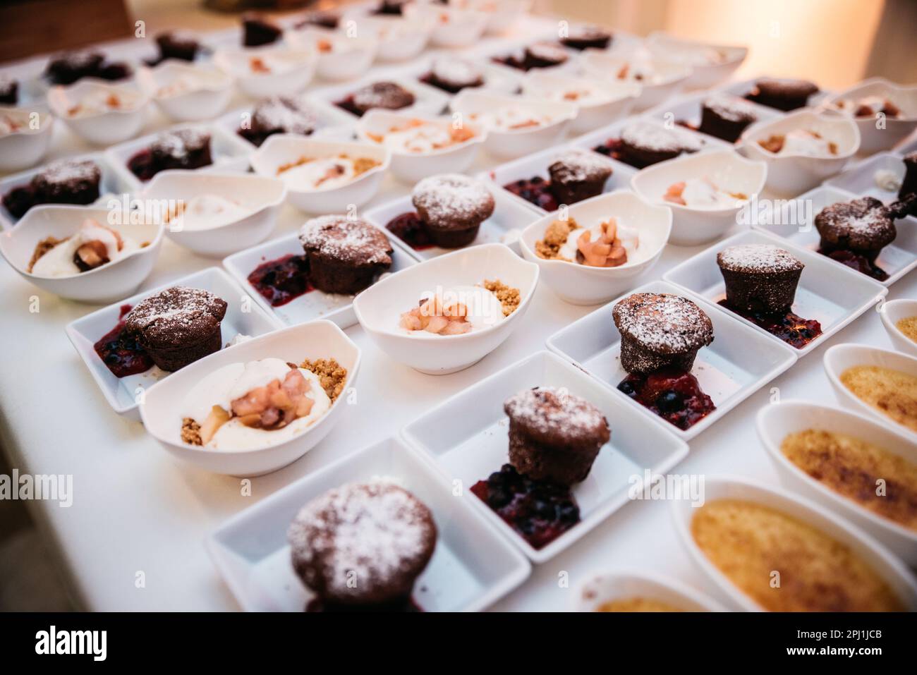 An array of delicious desserts are presented on a white table in shallow white bowls Stock Photo