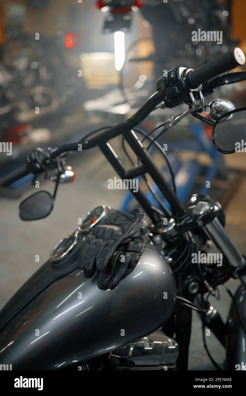 Motorcycle garage, closeup view on leather biker gloves on motorbike