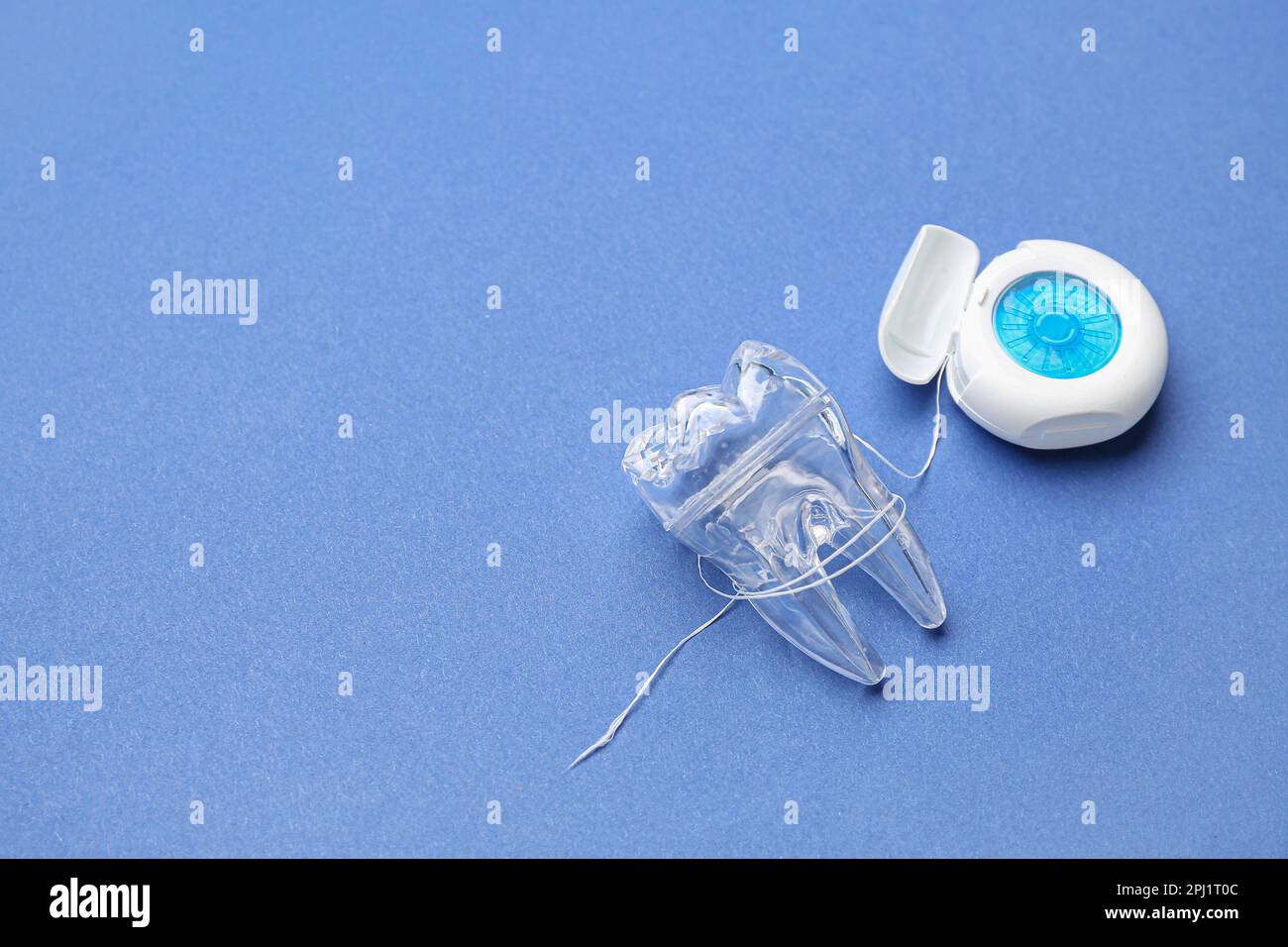 Case with dental floss and plastic tooth model on blue background Stock ...