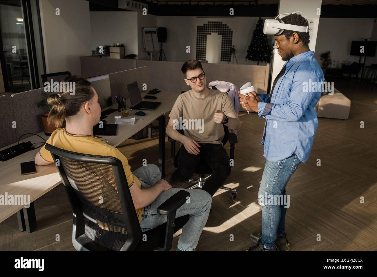 IT Development Team Working on VR Project. Man wearing VR headset, playing and touching something in the virtual world. Diverse men programmers using Stock Photo