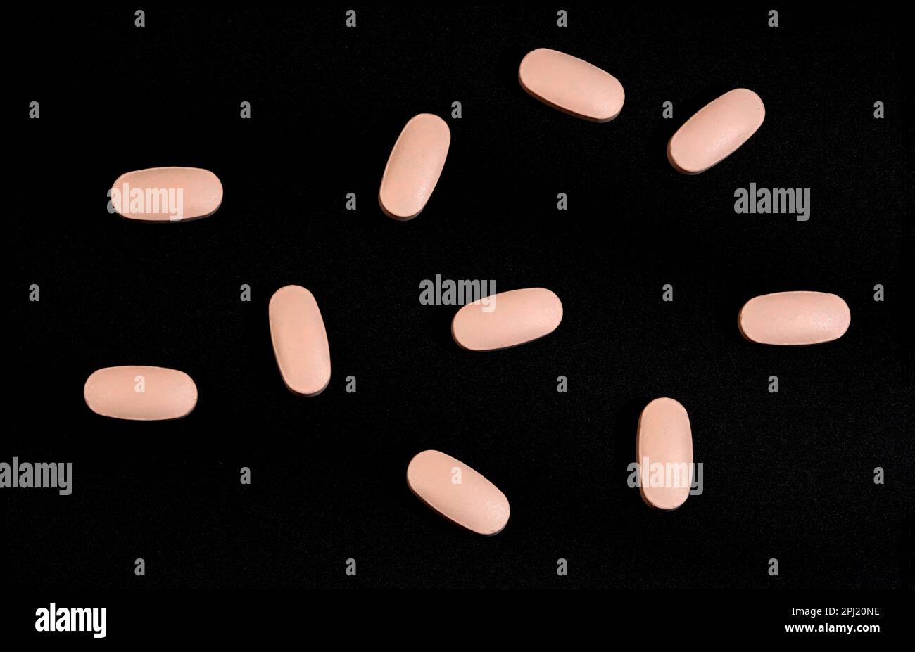 Scattered unspecified pink pills on a black background Stock Photo