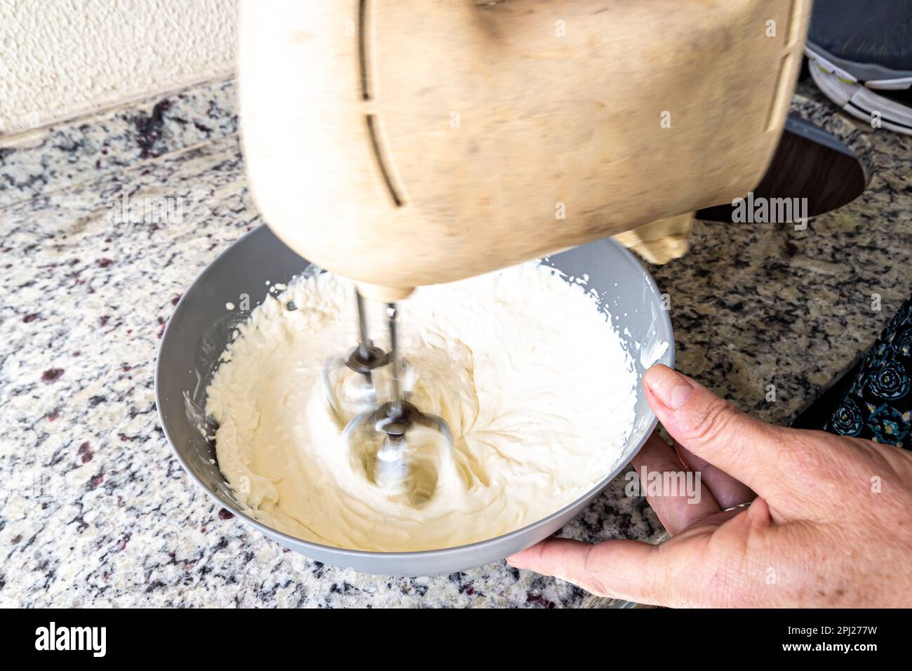 Electric mixer being used to prepare cheesecake ingredients. Family