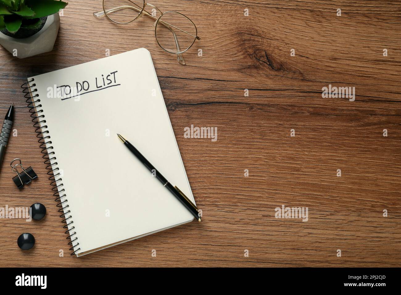 Flat lay composition with unfilled To Do list in notebook and glasses on wooden table, space for text Stock Photo