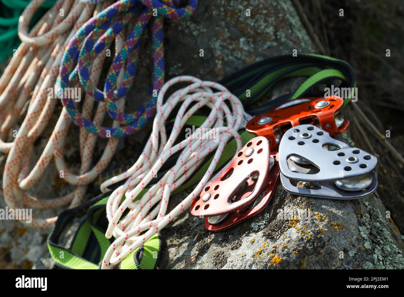 Different belay devices and ropes on rock, closeup. Climbing equipment