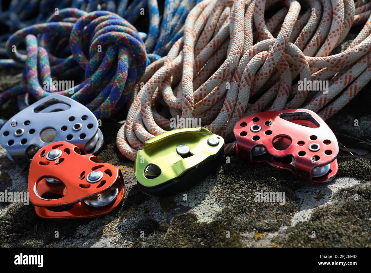 Different belay devices and ropes on rock, closeup. Climbing equipment