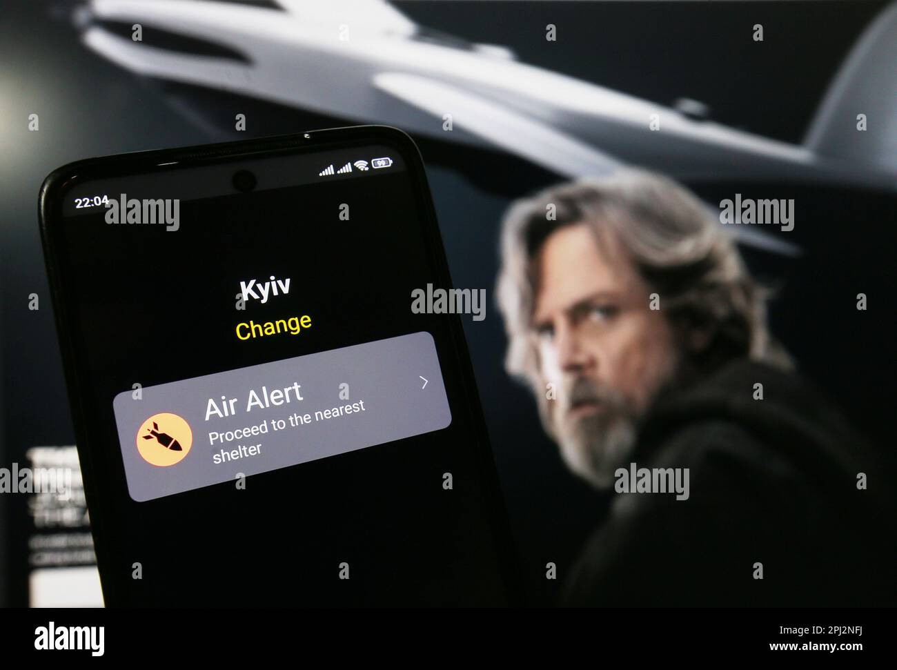 In this photo illustration, an Air Alert app is seen on a smartphone screen when the air raid alert sounds voiced by Star Wars actor Mark Hamill in front of the Ukrainian state website UNITED24. American actor Mark Hamill, known for his role as Luke Skywalker from the Star Wars films, decided to support the Armed Forces of Ukraine with equipment and announced raising funds towards 10 RQ-35 Heidrun reconnaissance drones for Ukrainian defenders, reported on the Ukrainian state website UNITED24, as the media said. When the air alert is canceled the actor's voice announces - 'May the Force be with Stock Photo
