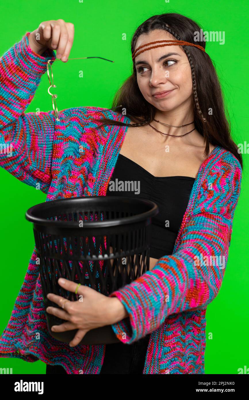Hippie woman taking off throwing out glasses into bin after medical vision laser treatment therapy surgery looking smiling at camera. Pretty girl isolated alone on chroma key background, green screen Stock Photo