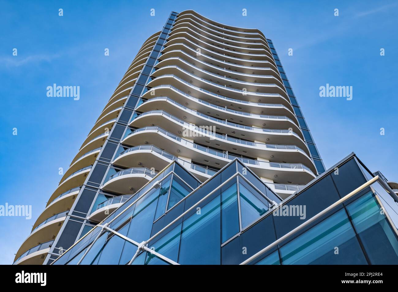 A highrise building against the blue sky. Condominium or apartment building. Looking Up Blue Modern Building. Architecture details Modern Building Gla Stock Photo