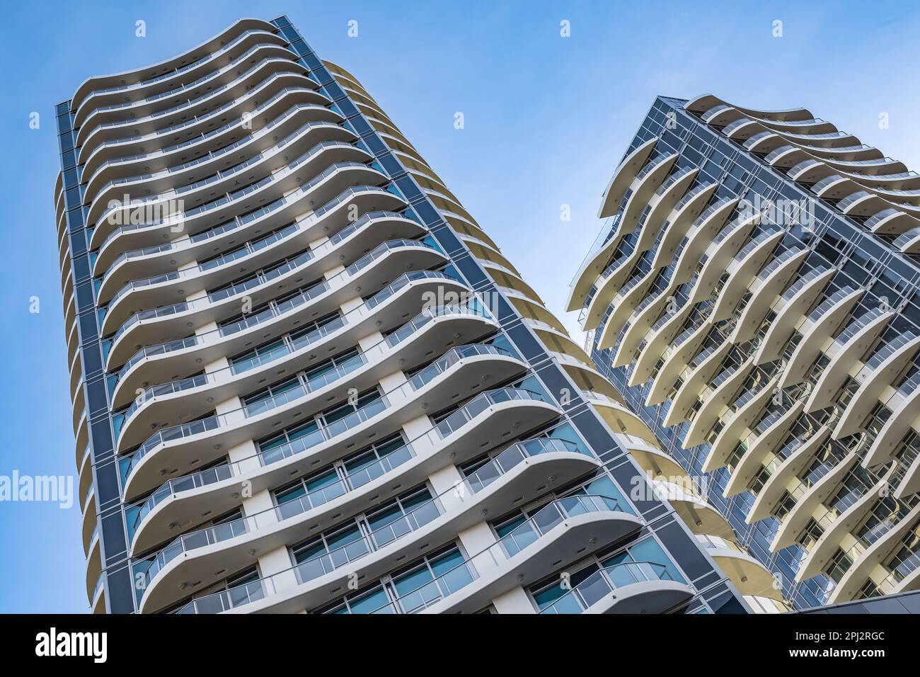 A highrise building against the blue sky. Condominium or apartment building. Looking Up Blue Modern Building. Architecture details Modern Building Gla Stock Photo