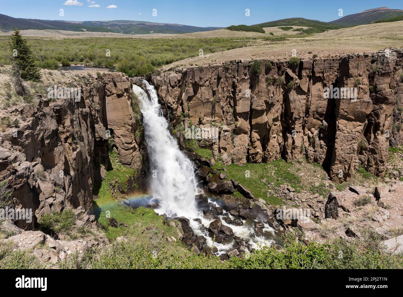 A Rainbow occurs from the spray of North Clear Creek Falls. The falls drop 100 feet and can be viewed along the Silver Tread Highway. Stock Photo
