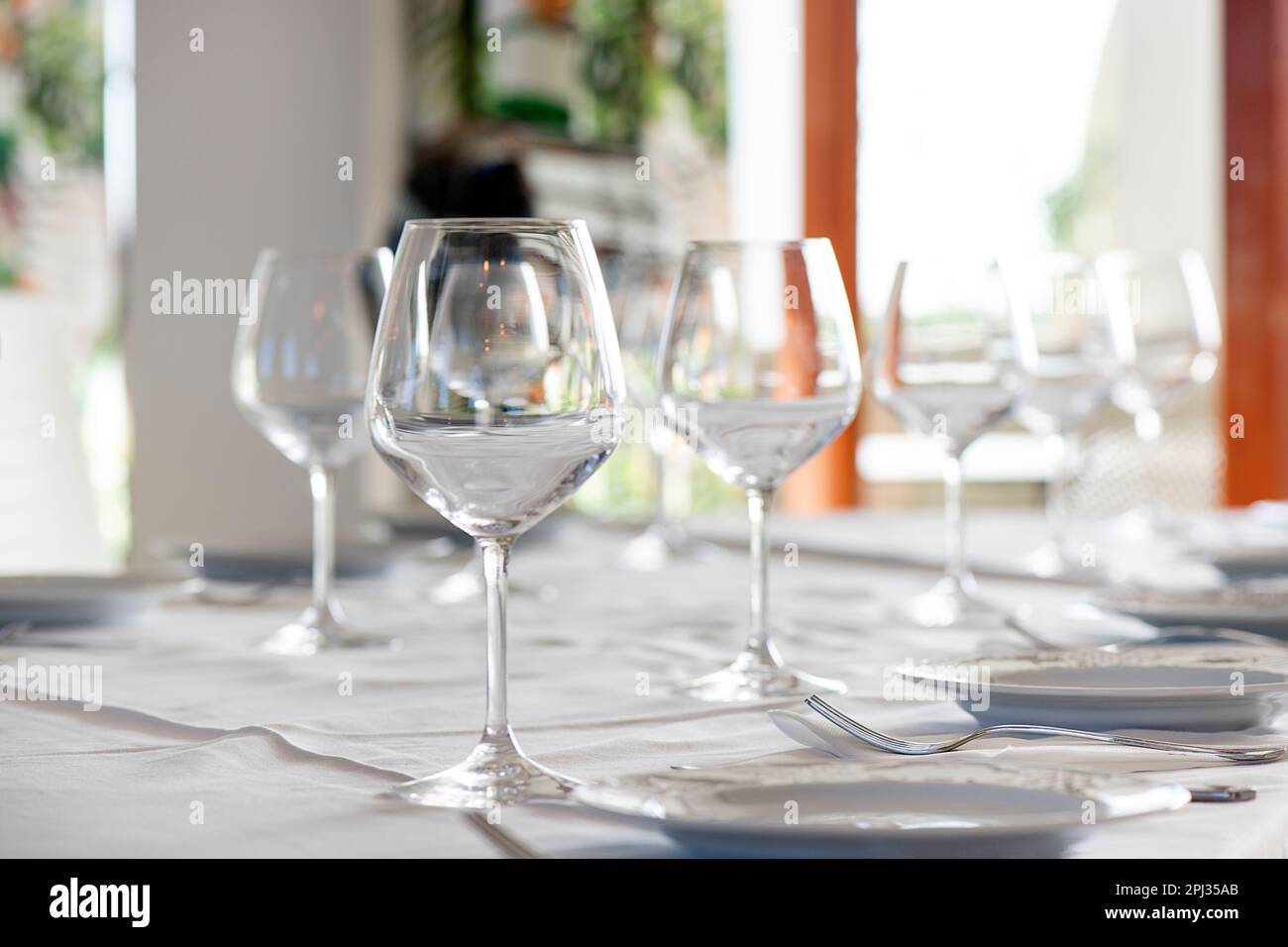 Table arrangement at a restaurant with sparkling crystal wine and water glasses, and starter plates, ready for a special event or a dining experience Stock Photo