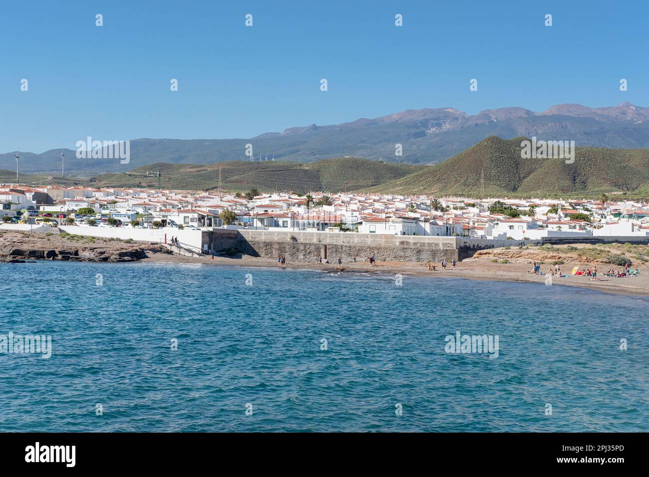Inland views of the peaceful sleepy town featuring quaint white houses with red rooftops and a small beach visited by few tourists, Abades, Tenerife Stock Photo