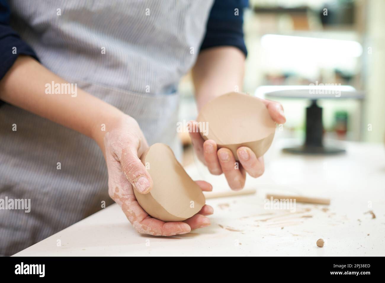 Female hands holding sliced clay ball for making ceramic goods in art pottery Stock