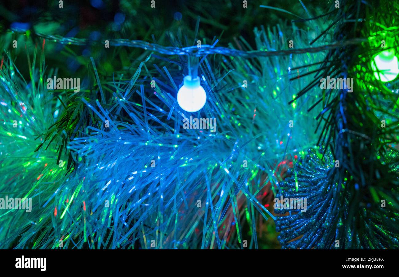 White sparkly tinsel hanging in the tree looking blue from Christmas