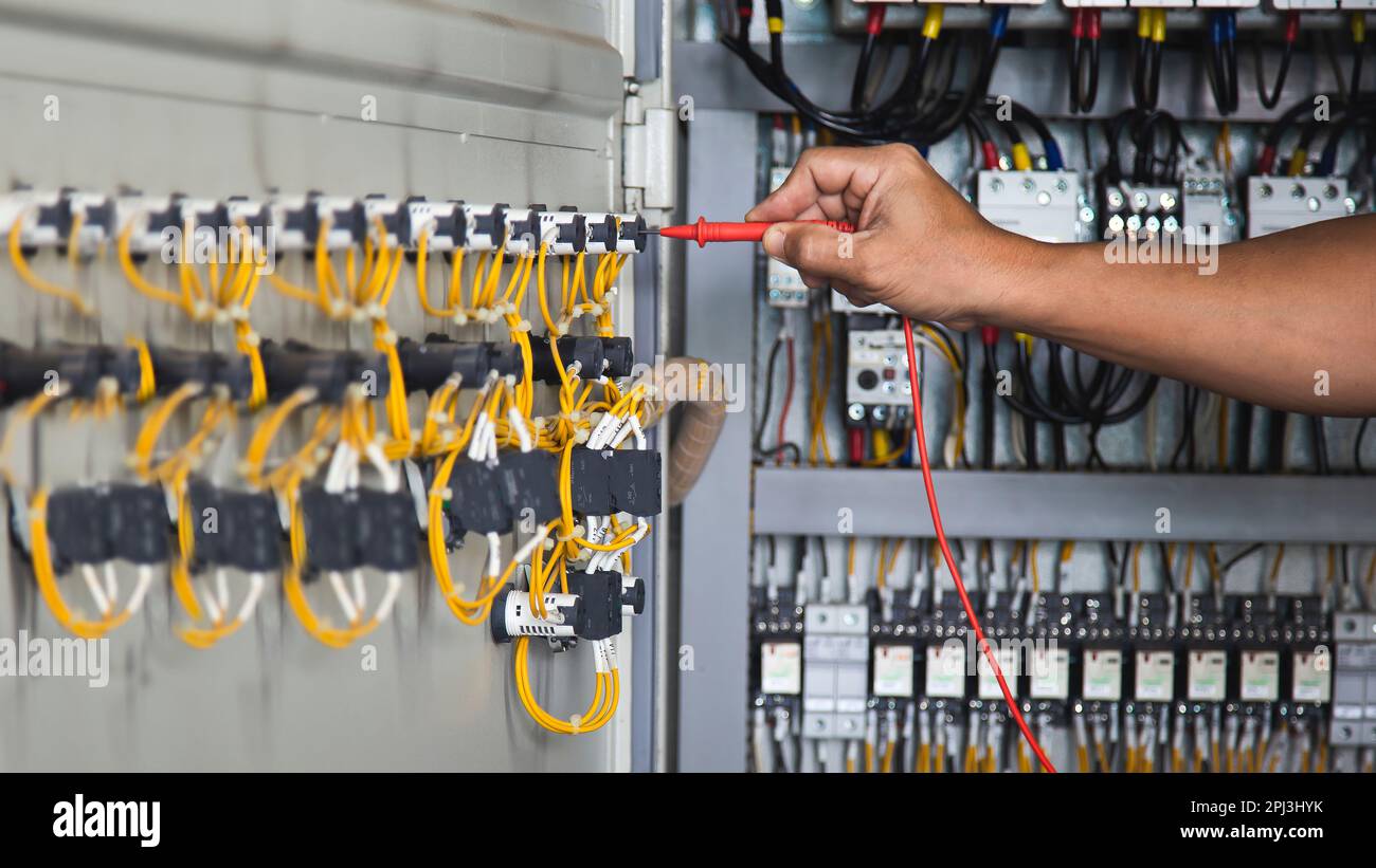 Electrical engineer checking the operation of electrical control cabinet, maintenance concept. Stock Photo