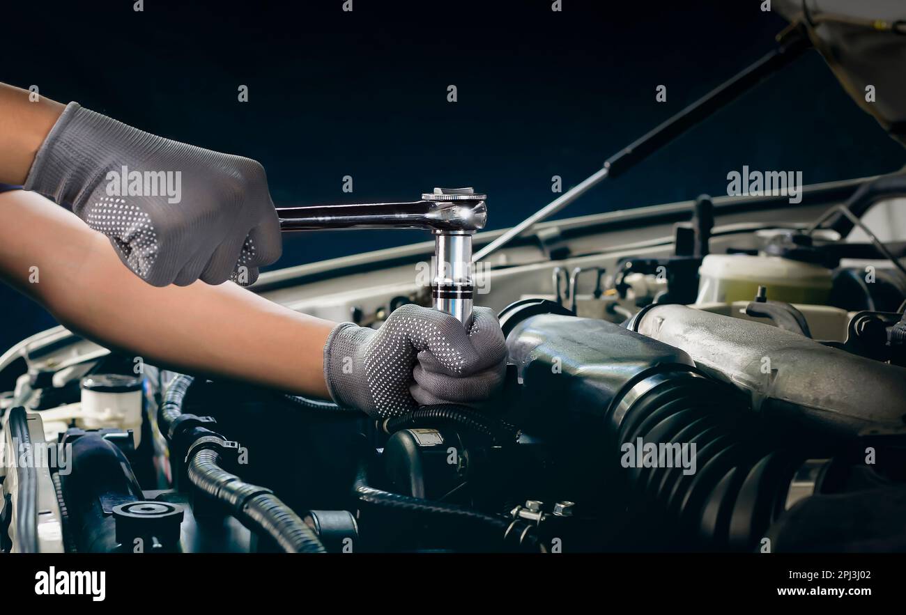 The mechanic works on the engine of the car in the garage, car repair