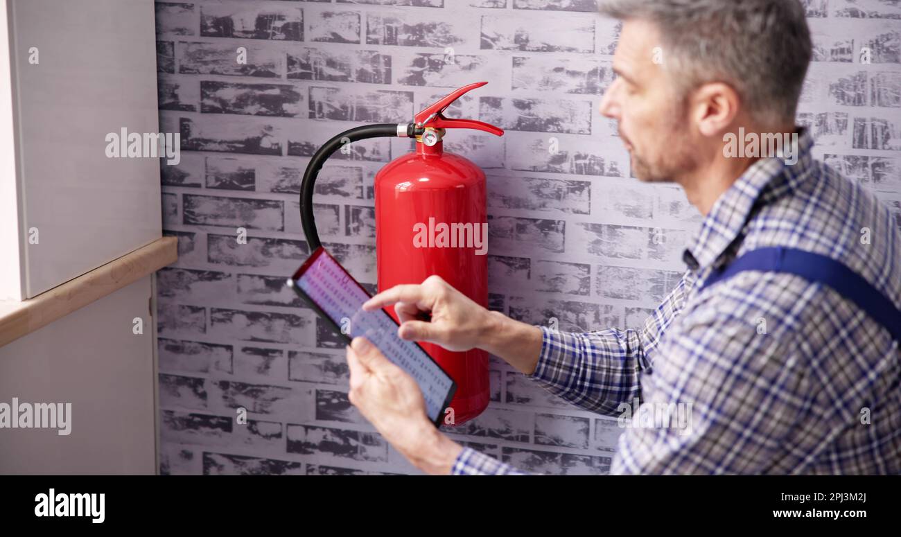 Worker Installing Fire Extinguisher. Inspection Service. Checking Security Label Stock Photo