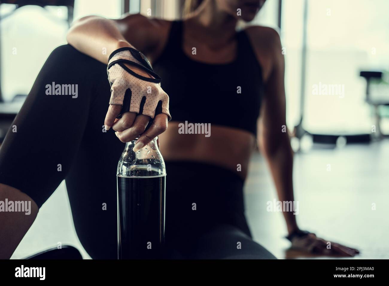 Young woman resting after gym workout holding a water bottle. Stock Photo