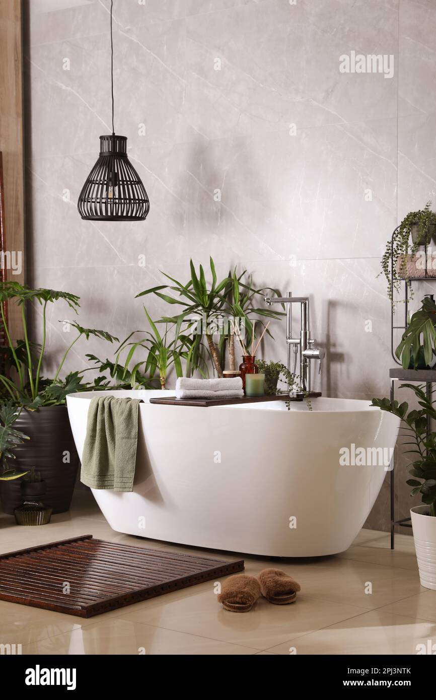 Modern white tub and beautiful green houseplants in bathroom. Interior ...