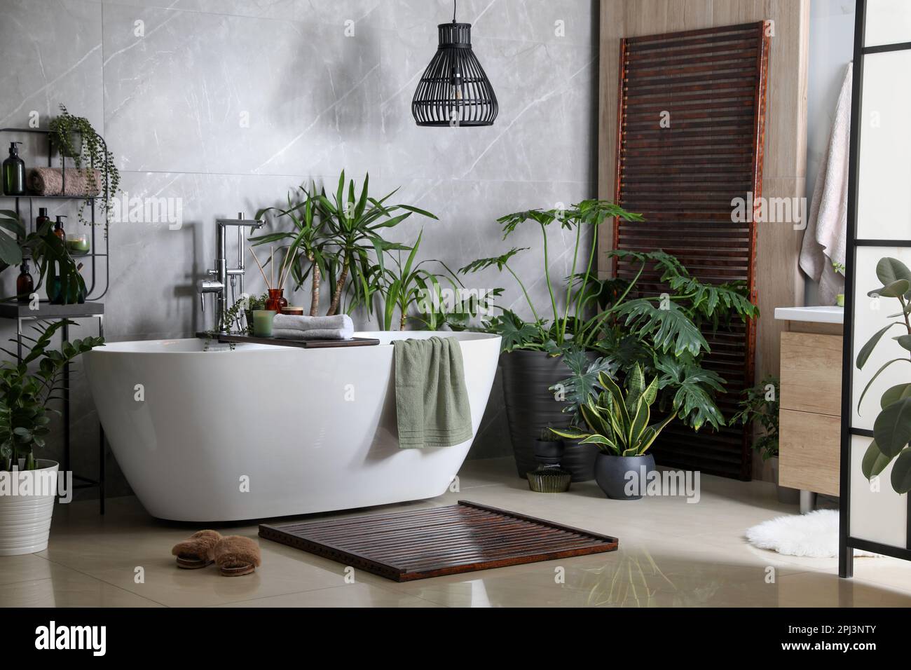 Modern white tub and beautiful green houseplants in bathroom. Interior ...