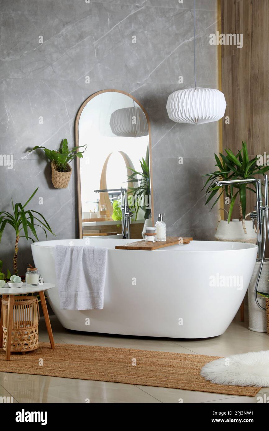 Modern white tub and beautiful green houseplants in bathroom. Interior ...