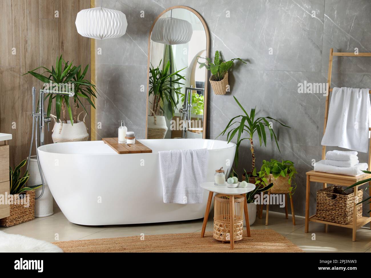 Modern white tub and beautiful green houseplants in bathroom. Interior ...