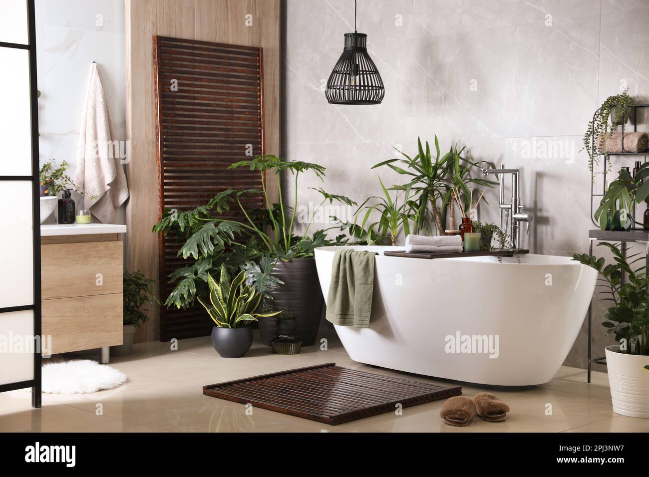 Modern white tub and beautiful green houseplants in bathroom. Interior ...