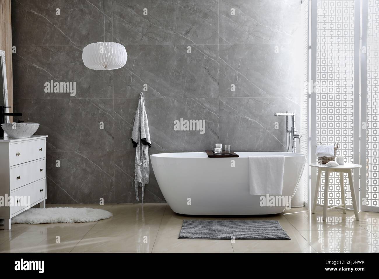 Modern white tub and chest of drawers with sink in bathroom. Interior