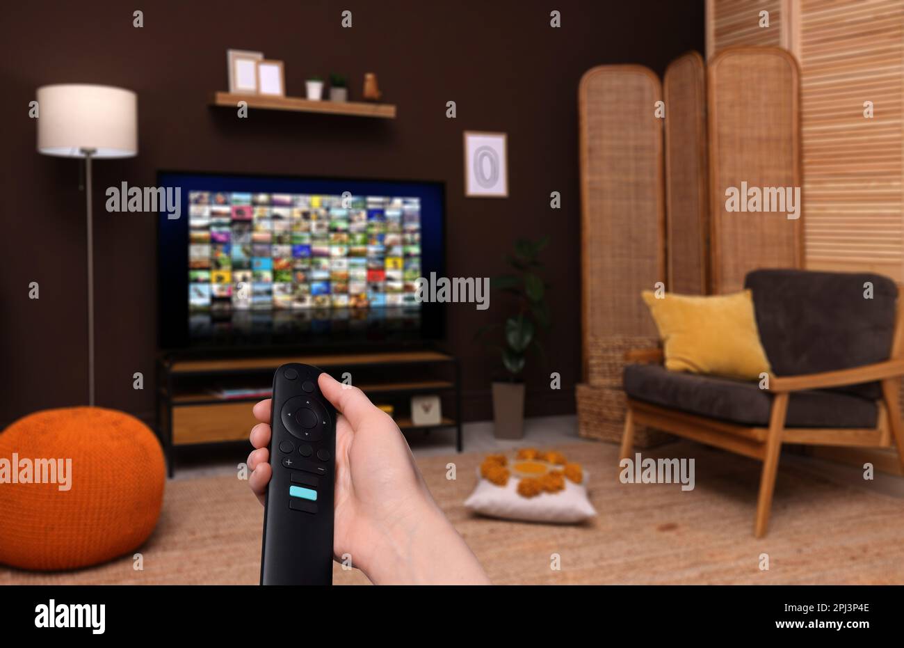 Woman with remote control changing channels while watching TV at home, closeup Stock Photo