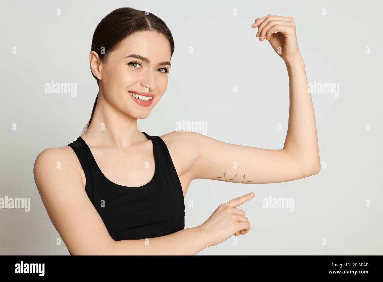 Slim young woman with marks on arm against light background. Weight