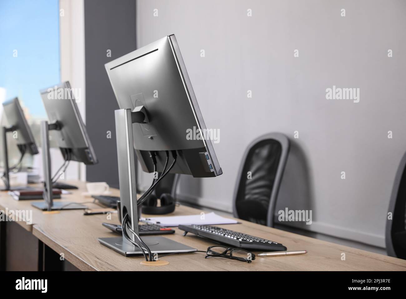 Open office interior. Modern workplaces with computers near light grey wall Stock Photo