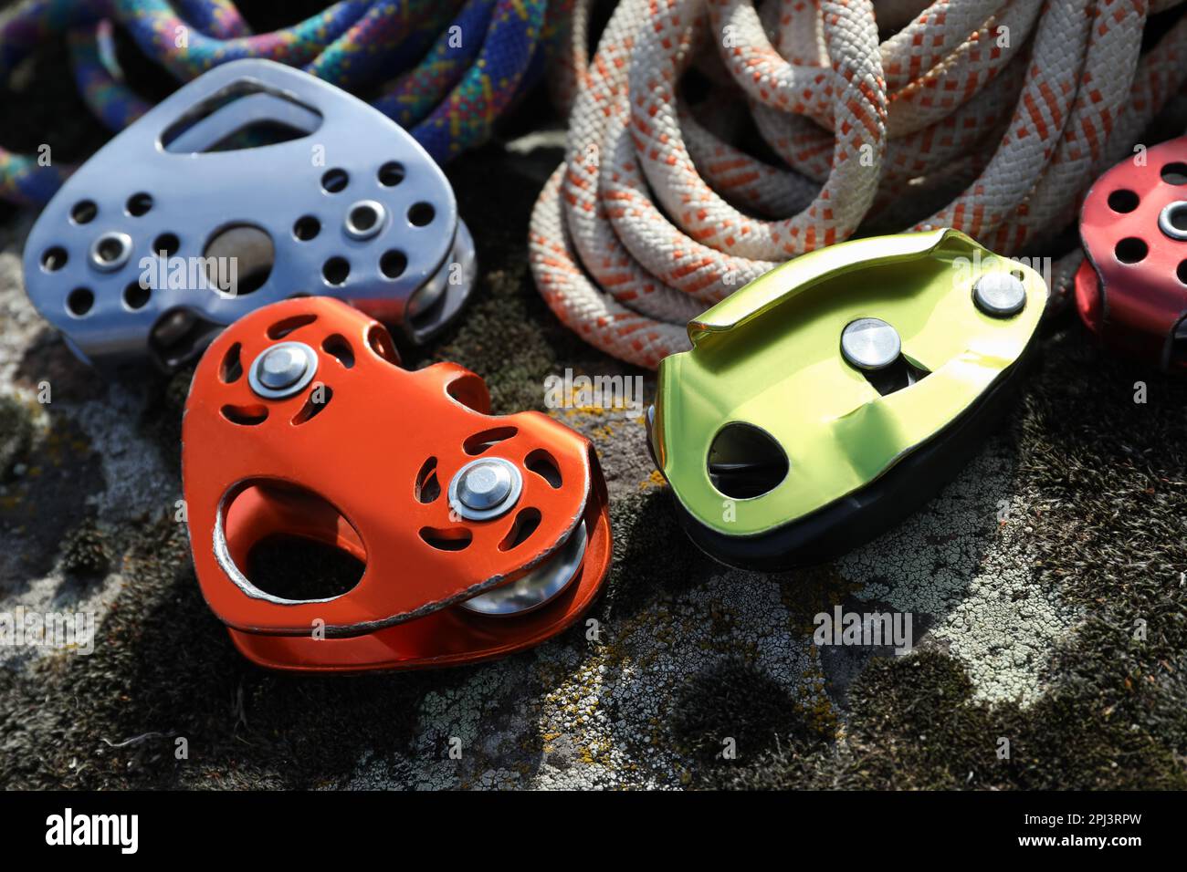 Different belay devices and ropes on rock, closeup. Climbing equipment