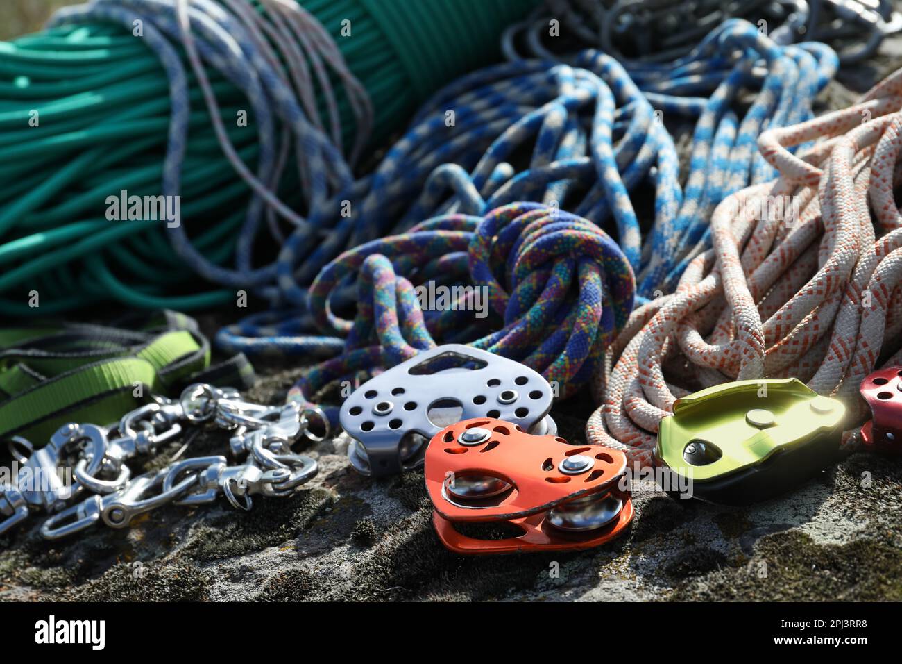 Different belay devices and ropes on rock, closeup. Climbing equipment